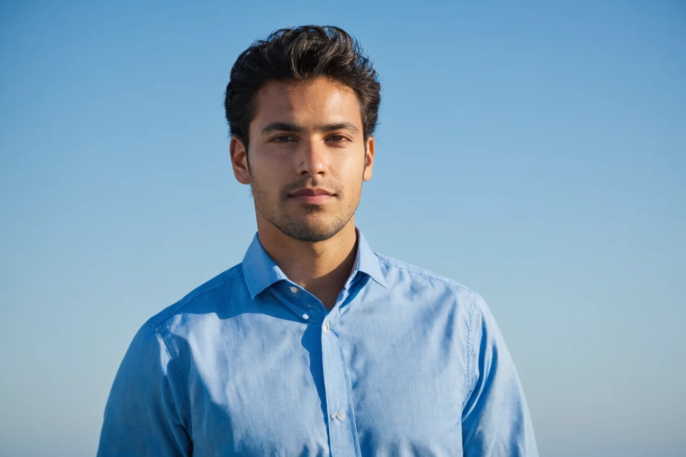 Man in blue shirt standing against clear blue sky