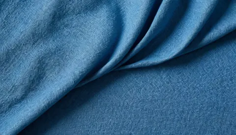 Rich blue textured fabric with soft folds and subtle sheen.