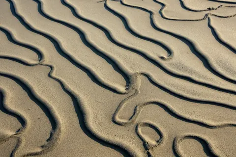 Ripples in golden sand casting deep shadows in a natural wave pattern