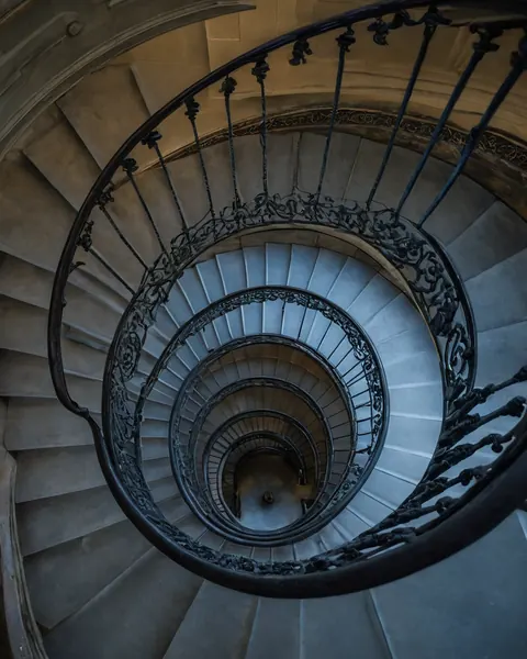 Spiral stone staircase with black iron railings viewed from above