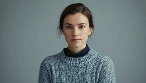 Young woman in blue knit sweater and dark turtleneck against gray background